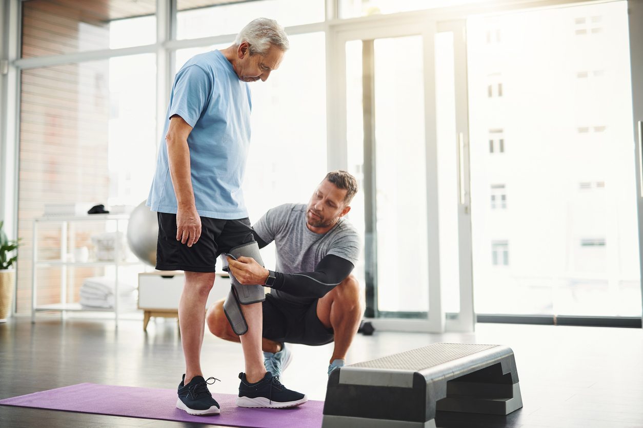 Specialist fits client with knee brace during physical therapy